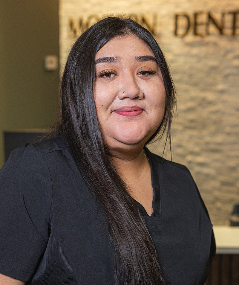 Young woman smiling at camera in Modern Dental office wearing black top